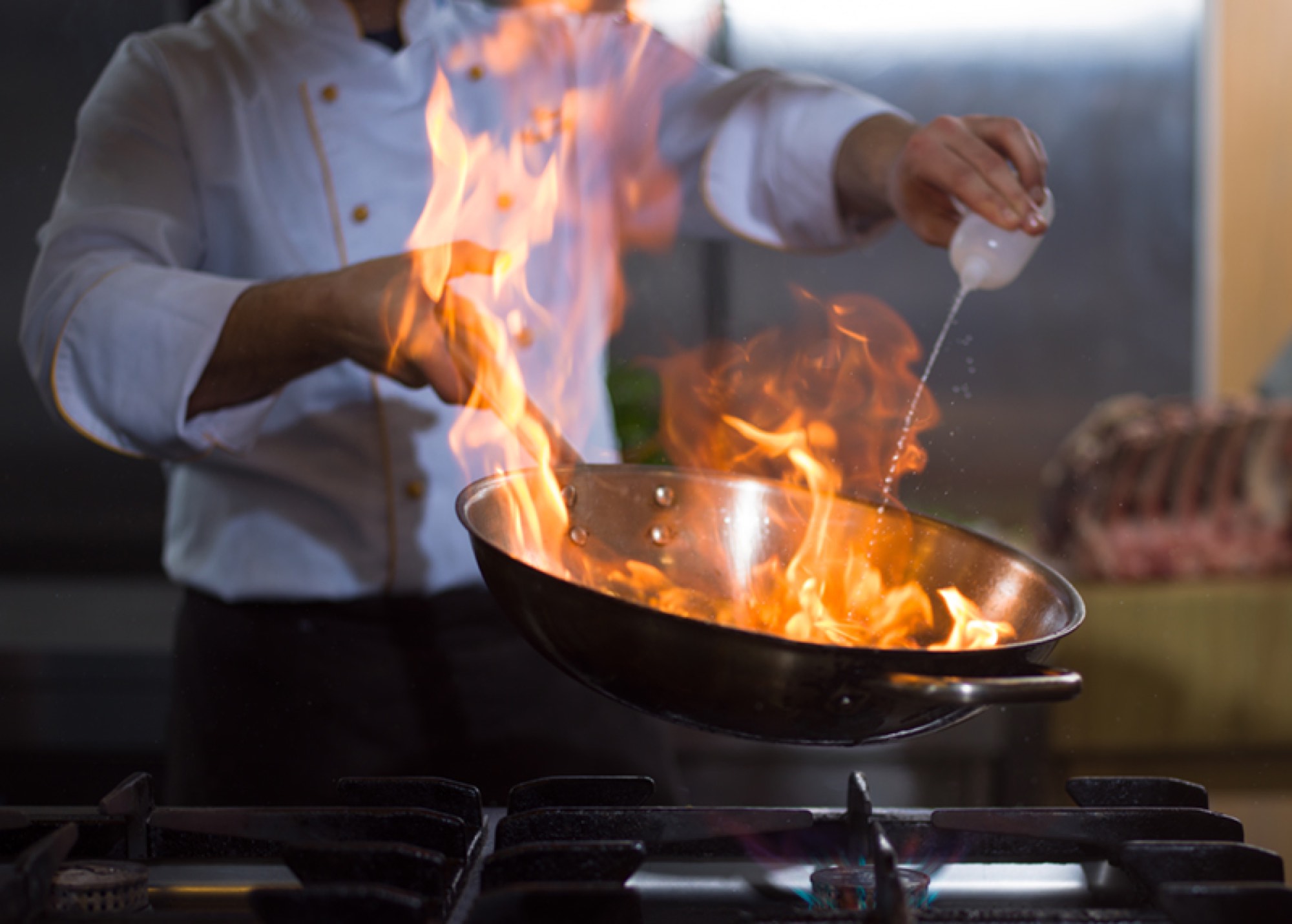 Chef flambéing in a pan at The Bell in Scona