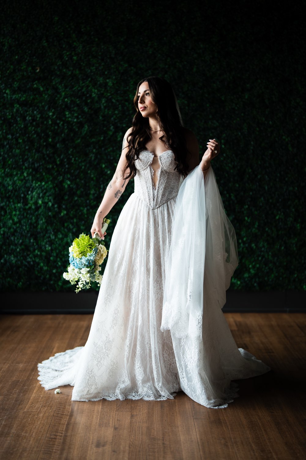 Bride with bouquet against the greenery wall